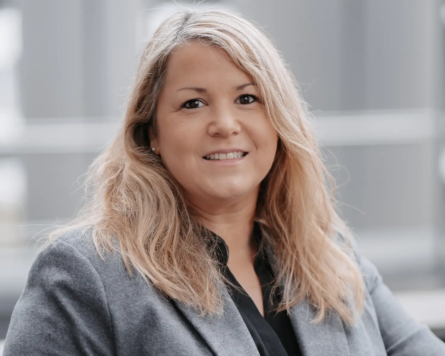 Eine Frau mit blondem Haar in einem grauen Anzug.